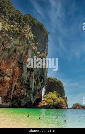 Una gigantesca formazione rocciosa si affaccia sulla sabbia bianca e sul mare blu di Railay Beach, a Krabi, Thailandia Foto Stock