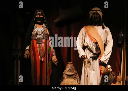 Mostra l'installazione presso il museo storico della tradizionale coppia di vecchia famiglia arabica. Donna che indossa abaya e battaglia nera maschera burka e uomo in bianco Foto Stock