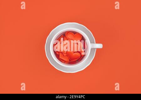 Tazza di tè bianca piena di cuori rossi Foto Stock