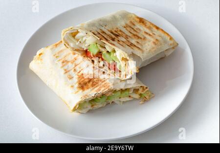 Shawarma, panino fatto in casa, su un piatto bianco, tagliato a metà. Foto Stock