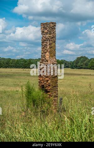 Il camino in pietra rustico è tutto ciò che rimane in piedi decadendo nel tempo da una vecchia fattoria che è andato a lungo nel sud rurale Foto Stock