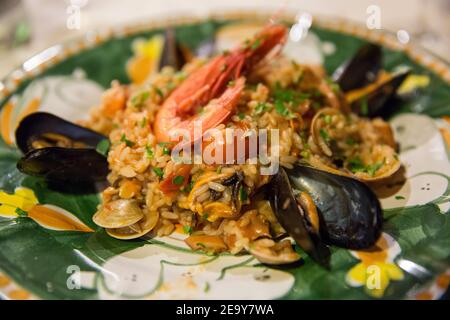 Cucina italiana: Risotto di pesce con gamberi alla griglia e cozze su un piatto di ceramica dipinta a mano dell'isola di Capri, Mar Tirreno, Italia Foto Stock