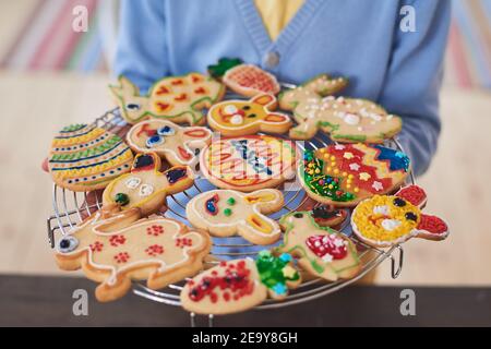 Primo piano di donna che regge vassoio con decorate biscotti al forno preparazione Per Pasqua Foto Stock