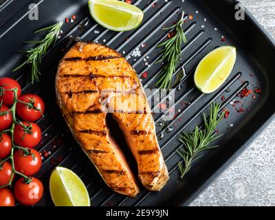 bistecca di salmone di pesce alla griglia, trota in una padella alla griglia, spezie, pomodoro, primo piano Foto Stock