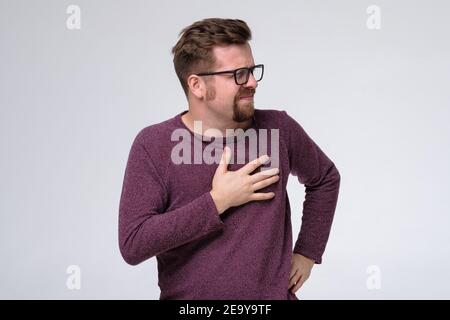 Uomo caucasico maturo che tiene la mano sul petto con dolore cardiaco. Scatto in studio Foto Stock