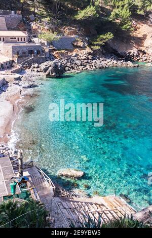 Onde che si infrangono sulla costa rocciosa delle montagne di Maiorca sullo sfondo, giornata di sole, nelle isole Baleari, Spagna Foto Stock