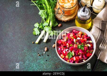 Concetto di cucina tradizionale russa. Vinaigrette di insalata di barbabietole con cetrioli sottaceto, fagioli, carote, piselli, crauti su un piano scuro. Copia spa Foto Stock