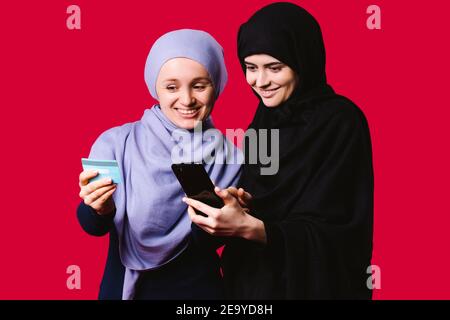 Eleganti donne arabe che tengono il telefono cellulare e la carta bancaria. Uomini d'affari con hijab elegante pagare con carta di credito mentre lo shopping online utilizzando il cellulare Foto Stock