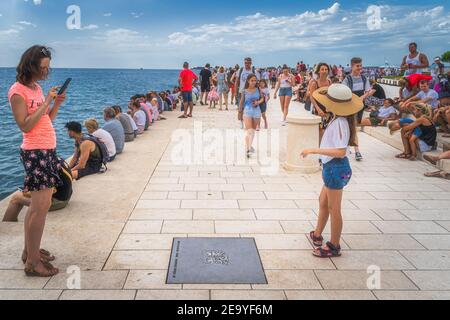 Zadar, Croazia, luglio 2019 folla di turisti ascoltano Sea orgulje, Morske orgulje, oggetto di arte sonora che suona musica attraverso onde di mare e tubi Foto Stock