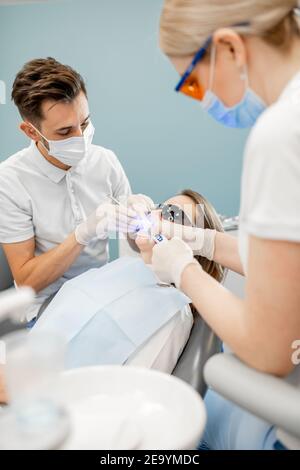 Dentista maschile e assistente utilizzando luce di cura dentale Foto Stock