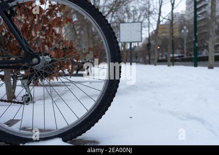 ruota in bicicletta su strada innevata e foglie secche Foto Stock