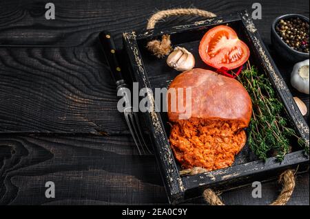 Mallorcan Sobrassada salumi di carne di maiale in un vassoio di legno sfondo di legno nero. Vista dall'alto. Spazio di copia Foto Stock