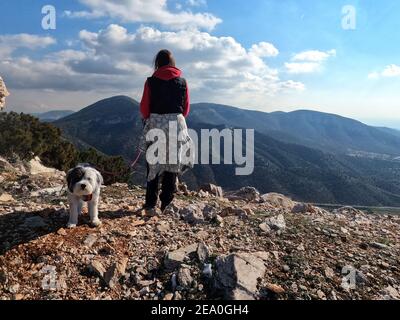 Donna escursionista con cane godendo la vista dal punto panoramico sul Monte Hymettus, vicino Atene, Grecia Foto Stock