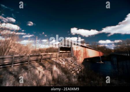 Il ponte coperto a Shieldstown, IN immagini in falso colore di luce infrarossa in un luminoso pomeriggio d'inverno. Il cielo è blu profondo e le nuvole sono soffici. Foto Stock