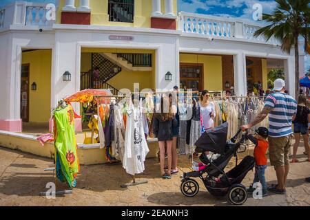 Cayo Santa Maria, Cuba, 2016 febbraio - turisti in una strada pedonale alla ricerca di buoni affari all'esterno di un negozio di souvenir di abbigliamento Foto Stock