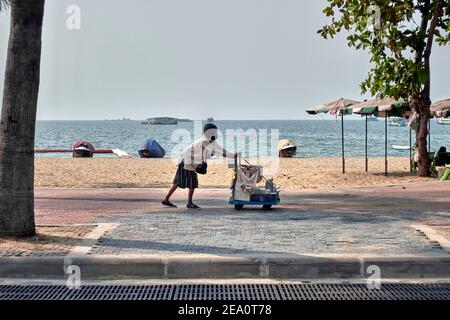 Persone anziane che lavorano. Donna anziana che spinge un carrello di bevande e cerca clienti lungo una spiaggia deserta. Thailandia Sud-est asiatico Foto Stock