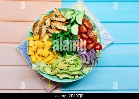 Colourful grande insalata di paleo con carne di pollo frilled e verdure fresche e frutta: Carne di mango gialla, avocado, cetriolo, pomodori ciliegia, lattu Foto Stock