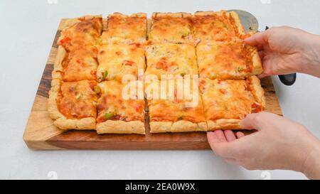 Le fette di pizza si avvicinano su una tavola di legno. Pizza vegetariana passo per passo ricetta Foto Stock