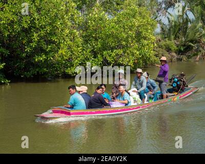 Gli agricoltori locali vengono trasportati su una tradizionale barca tailandese a coda lunga su un canale tra gli allevamenti di gamberetti e molluschi nella Samut Prakan Provincia di Thail Foto Stock