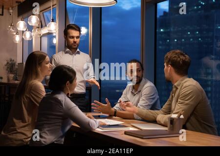 Un leader maschile sicuro coordina il lavoro di squadra di diversi gruppi di manager Foto Stock