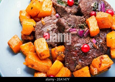 Bistecche di manzo cucinate con pezzi di zucca. Carne di vitello con salsa di mirtilli. Foto Stock