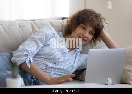 Donna caucasica rilassarsi sul divano utilizzando il computer portatile Foto Stock