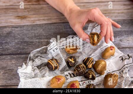 La mano della donna tiene le palle vegetariane di energia di cioccolato fatte in casa. Dolci sani a base di noci e fichi. Dessert vegetariano naturale fatto a mano. Foto Stock