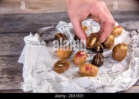 La mano della donna tiene le palle vegetariane di energia di cioccolato fatte in casa. Dolci sani a base di noci e fichi. Dessert vegetariano naturale fatto a mano. Foto Stock