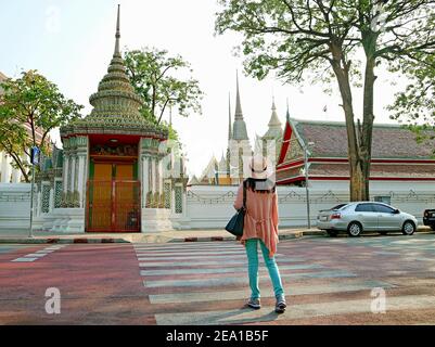 Donna che cammina sulla passerella che conduce alla splendida porta di Wat Pho o Tempio del Buddha reclinato, Bangkok, Thailandia Foto Stock