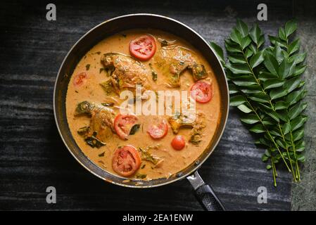 Vista dall'alto speziato stile Kerala stufato di curry di pesce e Appam Pesce Molee Meen Moilee cibo Indiano. Curry di pesce con peperoncino rosso al latte di cocco, foglie di curry, pomodoro. Foto Stock