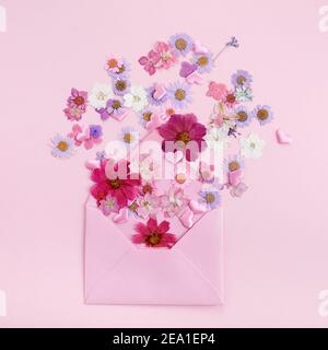 Avvolge con fiori colorati selvaggi su sfondo rosa. Concetto di amore. Disposizione piatta. Foto Stock