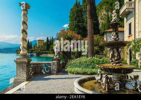 Splendida villa di vacanza fronte mare e giardino ornamentale. Vari fiori colorati e fontana nel giardino di villa Monastero, lago di Como, Lombardia, Foto Stock