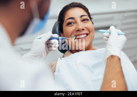 Vista sulla spalla di un medico dentista che tratta pazienti di sesso femminile. Donna che ha controllo dentale di routine presso il dentista. Foto Stock