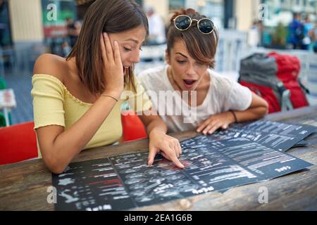 Due amici che ordinano in un caffè insieme dal menu Foto Stock