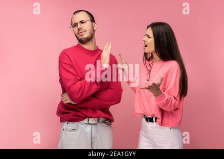 Foto di coppia sostiene e sembra infelice insieme, isolato su sfondo rosa Foto Stock