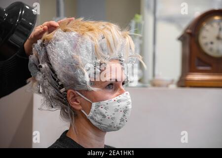 Una donna ha i suoi capelli tinti prima del blocco completo nel 2020 Foto Stock