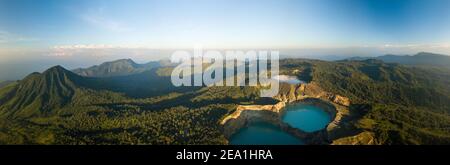 Vista panoramica aerea dei laghi vulcanici del cratere Kelimutu con acque turchesi e blu circondati da verdi montagne a Flores, Indonesia. Foto Stock