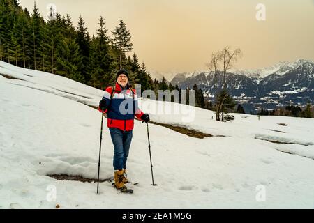 Escursione con le racchette da neve sul Walgau nel Vorarlberg innevato. Schneeschuhwanderung im Hochmoor über Sateins mit Saharasand am Himmel. Stadel Foto Stock