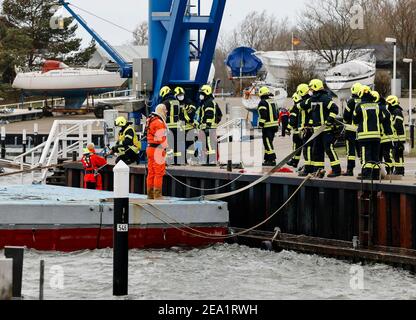 Strande, Germania. 07 febbraio 2021. Il personale di emergenza della vigili del fuoco volontario è in azione. Al porto, hanno assicurato un pontile di lavoro che ha causato danni alla parete della banchina a causa della tempesta. Venti di Gale-forza fino a 47 nodi hanno colpito la terraferma da est. Credit: Frank Molter/dpa/Alamy Live News Foto Stock