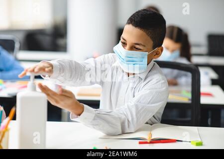 Ragazzino che applica l'igienizzatore antibatterico sulle mani Foto Stock