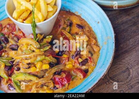 FAJITAS con pepe colorato e cipolle, servita con patatine fritte, salsa e panna acida. Foto Stock