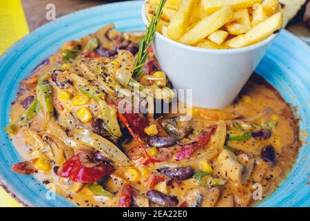FAJITAS con pepe colorato e cipolle, servita con patatine fritte, salsa e panna acida. Foto Stock