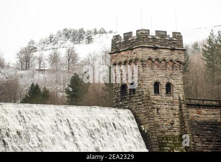 L'acqua scende lungo la diga di Derwent nel Peak District, con la neve pesante impostata per portare disagi al sud-est dell'Inghilterra e dell'Anglia orientale, mentre i venti amaramente freddi si aggrappano a gran parte della nazione. Data immagine: Domenica 7 febbraio 2021. Foto Stock