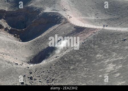 PARCO NAZIONALE DELL'ETNA, SICILIA, ITALIA - 18 OTTOBRE 2014: Un turista guarda alcuni dei tanti crateri sommitali dai quali esce un po' di fumo Foto Stock