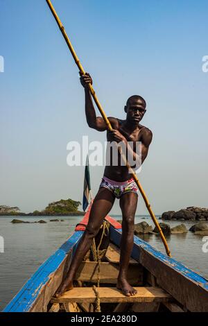 Uomo che spinge la sua piccola barca sulle isole Banana, Sierra Leone Foto Stock