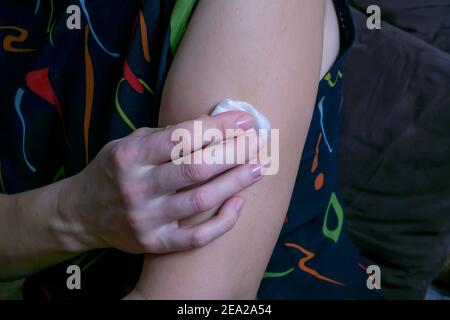 dopo l'iniezione nel muscolo della mano, la donna tiene un bastoncino di cotone Foto Stock
