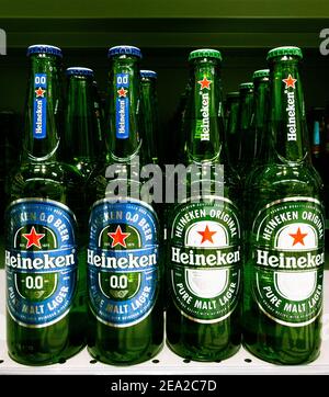 2021: Birre chiare in bottiglia Heineken in piedi nella mensola del supermercato Foto Stock