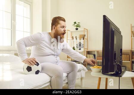 Uomo divertente che guarda la partita di calcio in televisione a casa e. mangiare popcorn Foto Stock