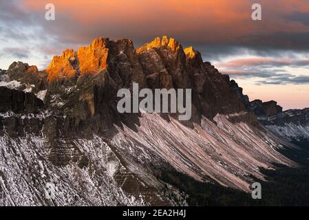 Nuvole, scogliere e le cime dei monti Puez-Odle brillano dorati al sole all'alba delle Dolomiti, della valle di Villnöß, del Sout Tirolo, Italia Foto Stock