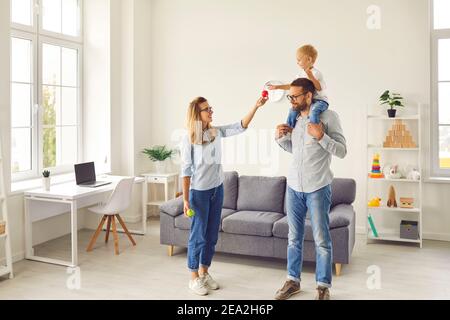 La famiglia felice con il figlio piccolo sulle spalle dei padri che soggiornano a. casa e gioco Foto Stock